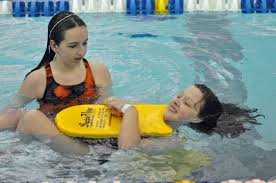 A lifeguard helping a swimmer in a pool.