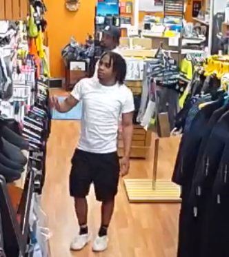 male wearing white shirt black shorts looking at merchandise