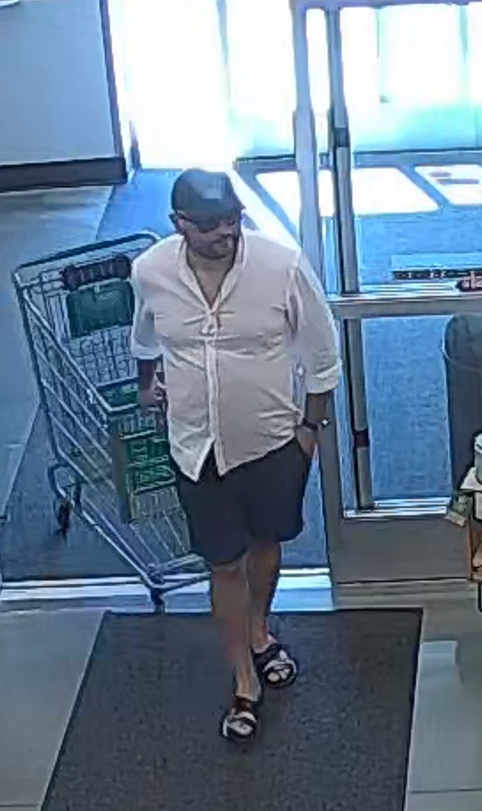 white male with black hat, white shirt, dark shorts in sandals pulling cart